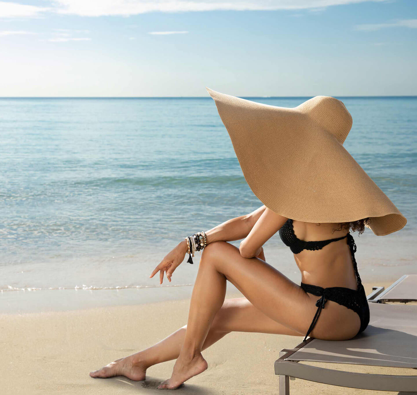 A woman in a hat sitting by the pool